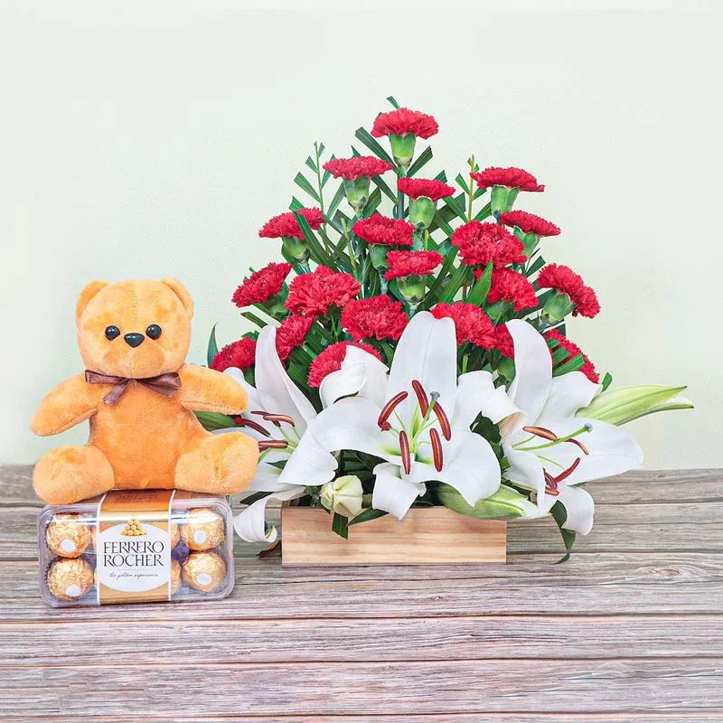 Teddy bear, Ferrero Rocher chocolates, and flowers on a wooden surface with a light background