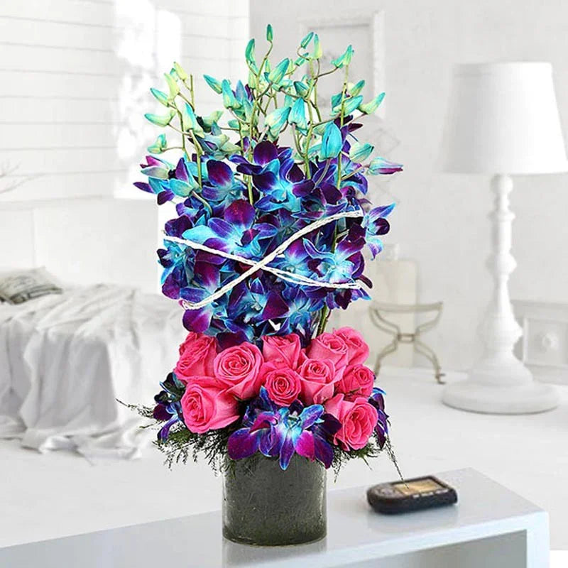 Bouquet of flowers with pink roses and blue orchids on a white surface.
