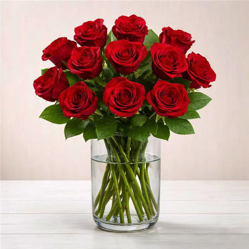 Bouquet of red roses in a clear vase on a light surface with a neutral background