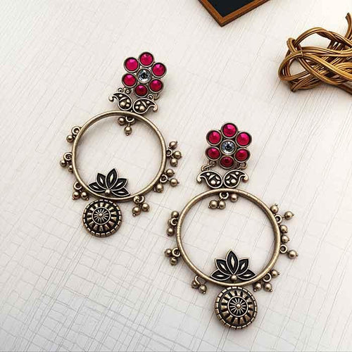 Ornate earrings with red gemstones on a white surface