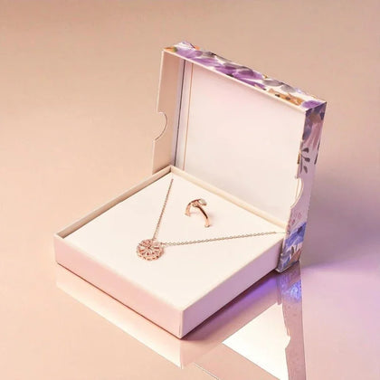 Rose gold necklace and ring in a jewelry box on a pink background