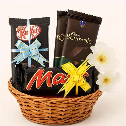 Basket of chocolate bars including KitKat, Cadbury Bourneville, and Mars with a white flower on a white background