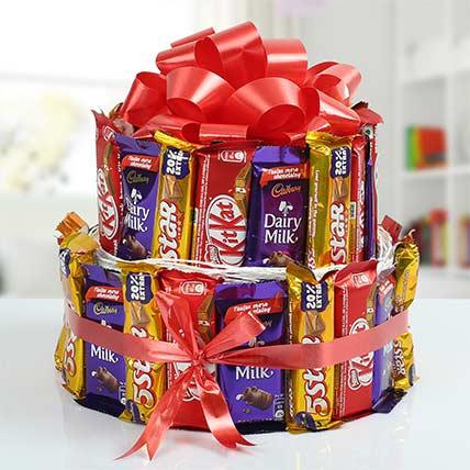 Two-tier chocolate bouquet cake made of assorted KitKat, Dairy Milk, and 5 Star bars, topped with a large red bow.