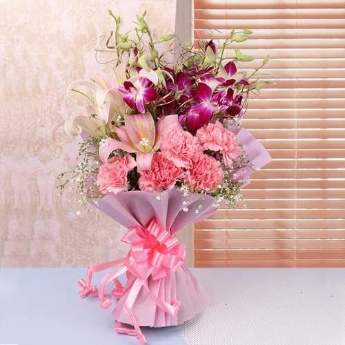 Elegant flower bouquet with pink roses, lilies, orchids, and greenery wrapped in pink paper