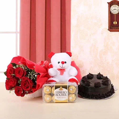 Bouquet of red roses, teddy bear, Ferrero Rocher chocolates, and black cake on a table with a clock in the background.