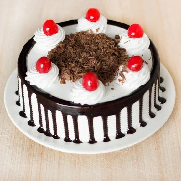 Black forest cake with whipped cream, cherries, chocolate shavings on a white plate
