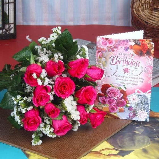 Pink rose bouquet with white fillers and a floral birthday greeting card on table