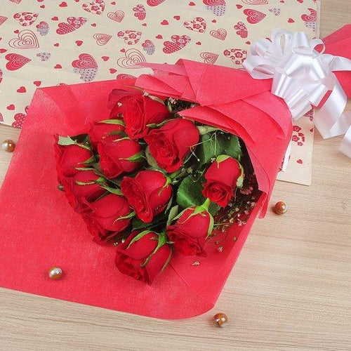 Bouquet of red roses wrapped in red paper with a white bow 