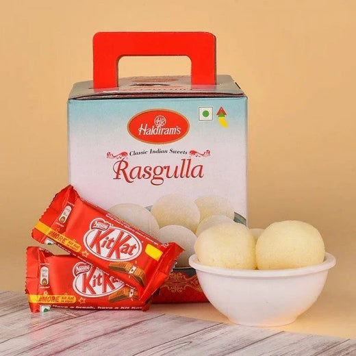 Box of Haldiram's rasgulla, two KitKat chocolate bars, bowl with three rasgullas on table
