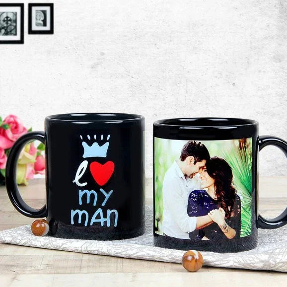 Two black mugs with personalized designs on a wooden surface.