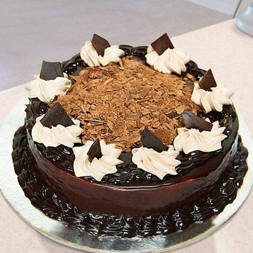 Chocolate cake with white frosting and chocolate shavings on a white plate.