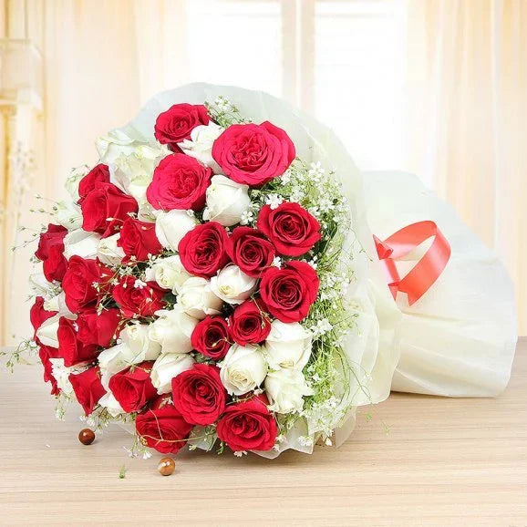 Bouquet of red and white roses with a red ribbon on a light background