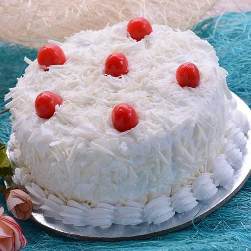 White cake with red cherries on a blue textured surface