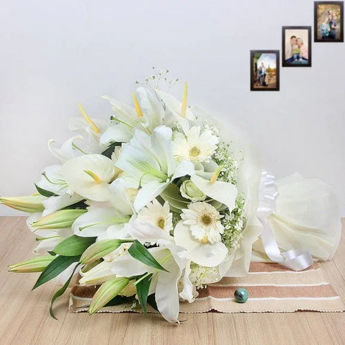 Bouquet of white flowers on a wooden surface with family photos