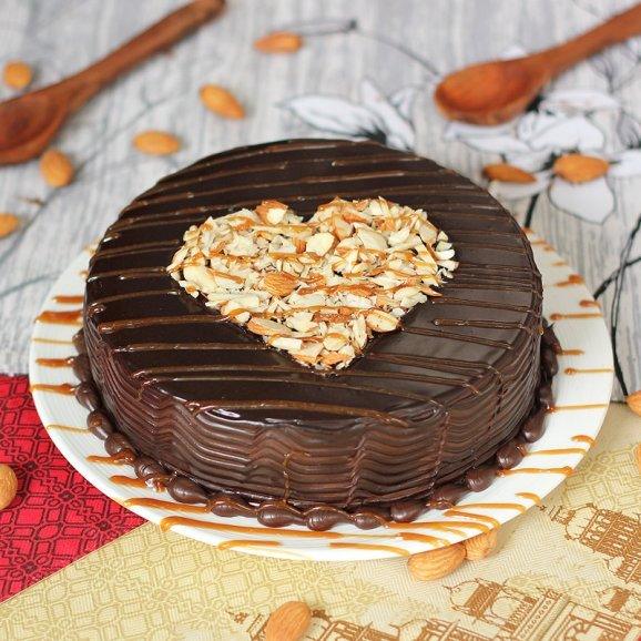 Chocolate cake with a heart-shaped topper on a decorative tablecloth.