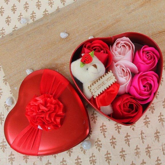 Heart-shaped box with a teddy bear and roses on a patterned surface