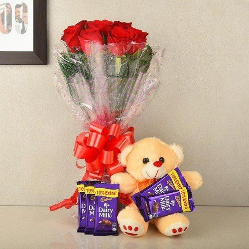 Bouquet of red roses with a teddy bear and Cadbury Dairy Milk chocolate bars on a light background