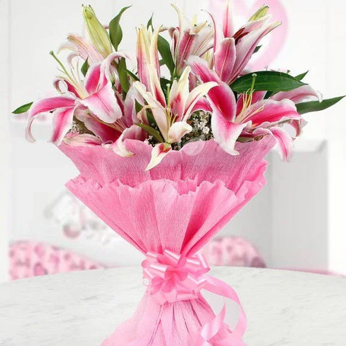 Bouquet of pink flowers wrapped in pink paper with a bow on a white background