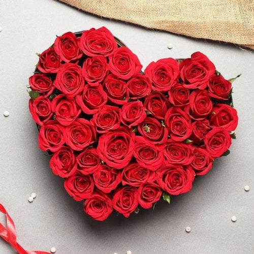 Heart-shaped arrangement of red roses on a light gray background
